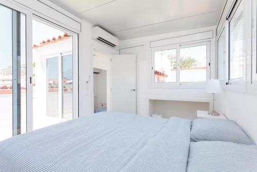 a white bedroom with a large bed and windows at Apartment Port D'aiguadolç Sitges in Sitges