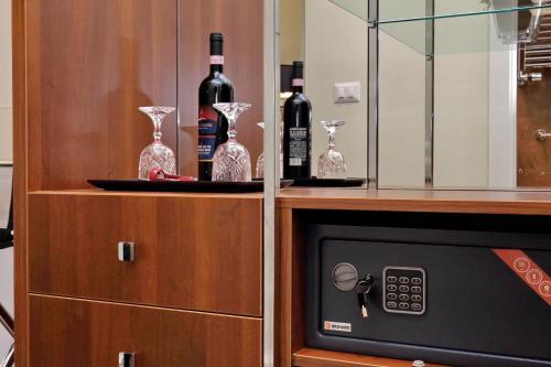 a cabinet with bottles of wine and wine glasses at Piazza Venezia Grand Suite in Rome