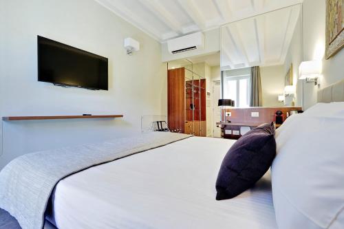 a bedroom with a large white bed with a tv on the wall at Piazza Venezia Grand Suite in Rome
