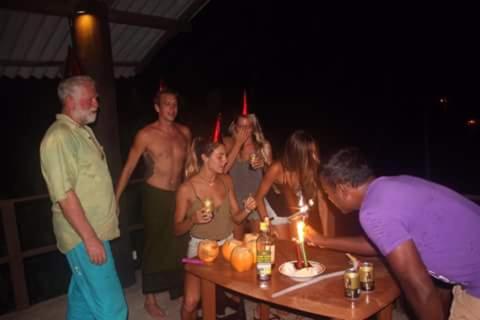 a group of people standing around a table with a birthday cake at Sunset Surfing Beach Resort in Matara