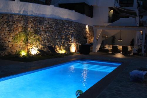 una piscina notturna con un muro di pietra di Casa Altos 39 a La Herradura