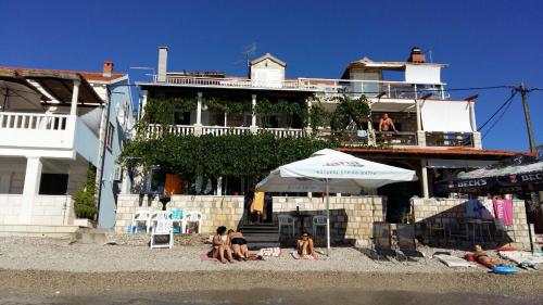 eine Gruppe von Menschen, die unter einem Sonnenschirm am Strand sitzen in der Unterkunft Apartments Luna in Žuljana