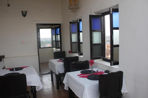 een eetkamer met tafels en stoelen en ramen bij Hotel Shahi Garh in Jaisalmer