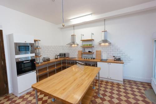 a large kitchen with a wooden table in it at Cohort Hostel in St Ives