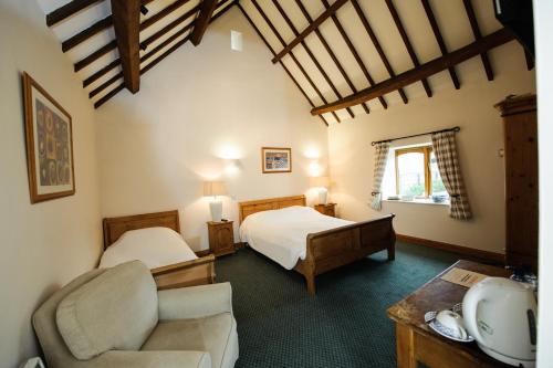 a bedroom with two beds and a couch and a chair at Church Farm Lodge in Harrington
