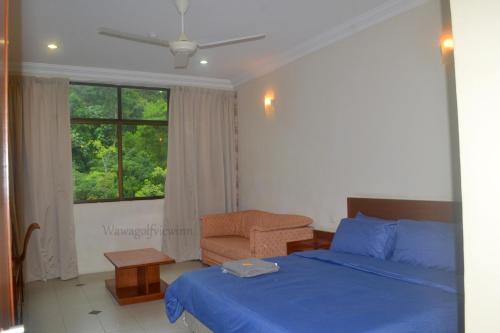 a bedroom with a bed and a chair and a window at Wawa's Golf View Inn in Taiping