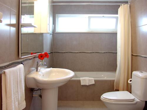 łazienka z umywalką, toaletą i oknem w obiekcie Apartamentos Maritur w Albufeirze