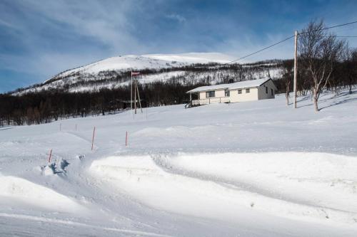 a house on a snow covered slope with a mountain at Seljenes Cottage in Russenes