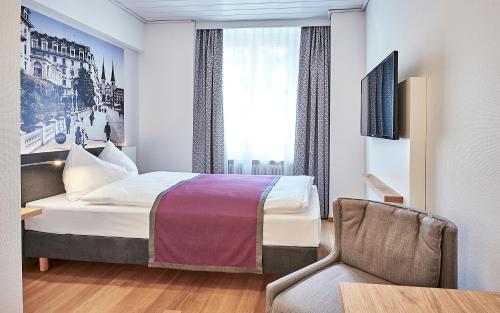 a hotel room with a bed and a chair at Hotel Central Luzern in Luzern