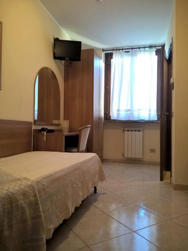 a bedroom with a bed and a desk and a window at Hotel Rocco in Carugate