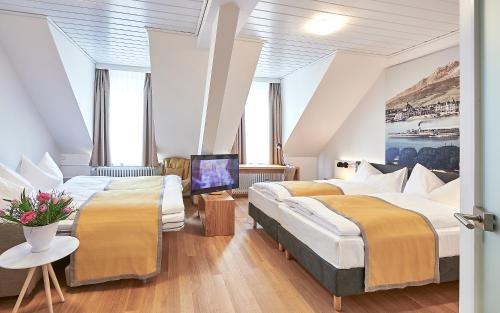 a hotel room with two beds and a television at Hotel Central Luzern in Luzern