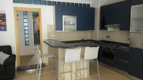eine Küche mit blauen Schränken und weißen Barhockern in der Unterkunft Appartamento Teodorico in Verona