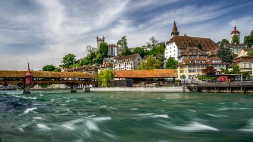 a river with a bridge in front of a city at Hotel Central Luzern in Luzern