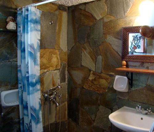 a stone bathroom with a shower and a sink at Drapanias BeachFront Apartments - Marinakis in Kissamos
