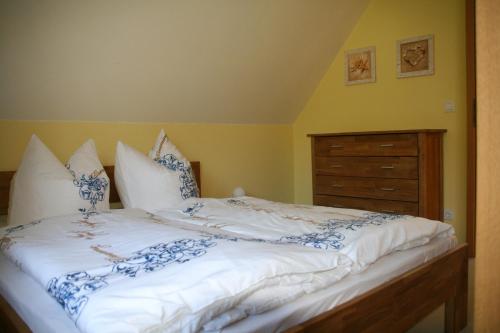 a bed with blue and white sheets and a dresser at Ferienhaus Dierhagen Strand I & II in Dierhagen