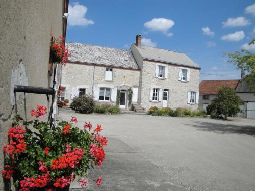 a house with red flowers in front of it at Ferme de La poterie in Donnery