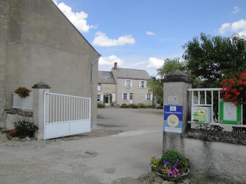 a building with a white gate and a building with flowers at Ferme de La poterie in Donnery