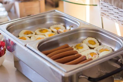 a pan with eggs and hot dogs and sausages at Hotel MAGISTR Vsetín in Vsetín