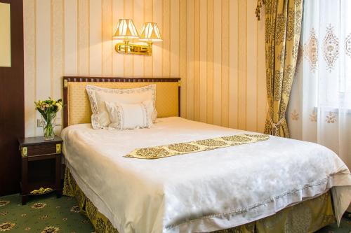 sypialnia z dużym łóżkiem z białą pościelą i oknem w obiekcie Palace Hotel Polom w Żylinie