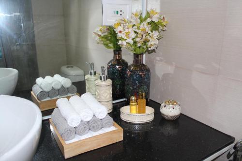 ein Badezimmer mit einer schwarzen Theke mit Handtüchern und Blumen in der Unterkunft Wind Residences Tower 4 in Tagaytay