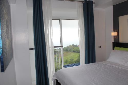 um quarto com uma cama e uma grande janela em Wind Residences Tower 4 em Tagaytay