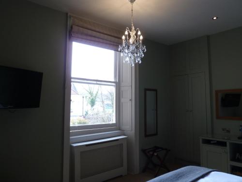 a bedroom with a window and a chandelier at Edgar Townhouse in Bath