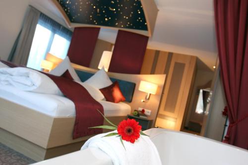 a bedroom with two beds and a red flower on a table at Villa Ludwig Suite Hotel in Hohenschwangau