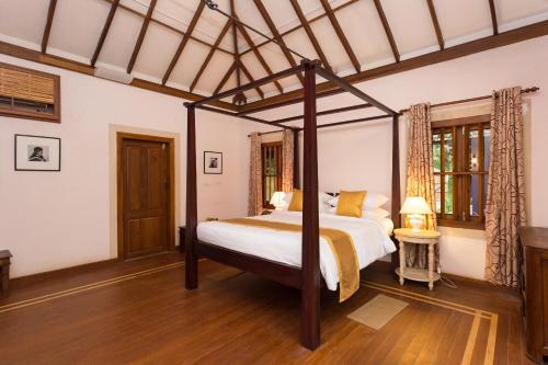 a bedroom with a four poster bed in a room at Azure Tides Marari in Mararikulam