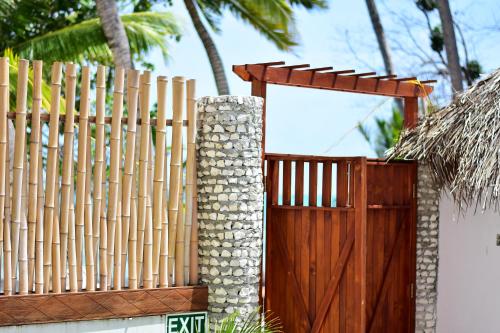 a wooden fence with a wooden gate and a tree at Veli Vilaa in Dhiffushi