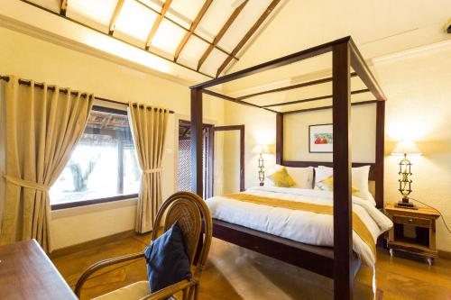 a bedroom with a canopy bed and a table and chairs at Azure Tides Marari in Mararikulam
