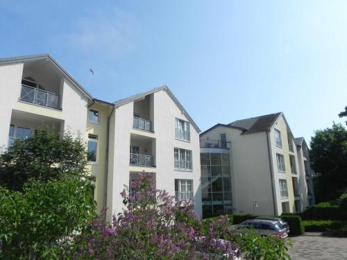 twee appartementsgebouwen op een parkeerplaats met paarse bloemen bij Ferienwohnung 1 2 14 Inselstrand in Ahlbeck