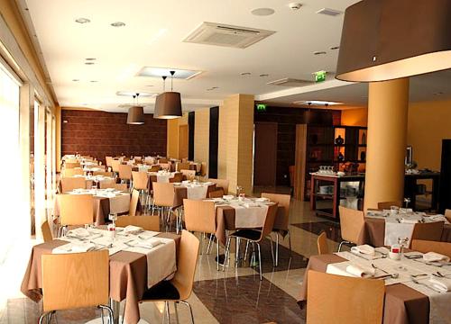 uma sala de jantar com mesas e cadeiras num restaurante em Hotel O Novo Principe em Almeirim