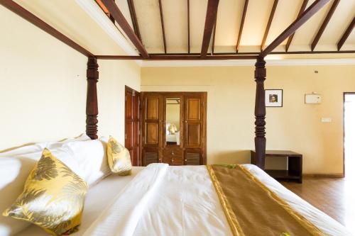 a bedroom with a large bed with white sheets and gold pillows at Azure Tides Marari in Mararikulam