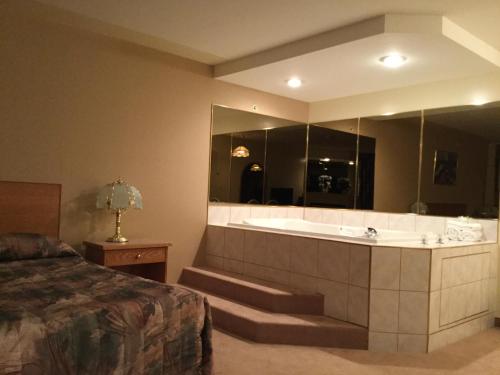 a large bathroom with a tub and a bed at Western Budget Motel #1 Grande Prairie in Grande Prairie