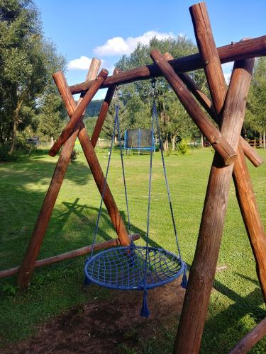 a swing set with a wooden frame in a park at Zajazd Stodoła sauna w cenie in Stronie Śląskie