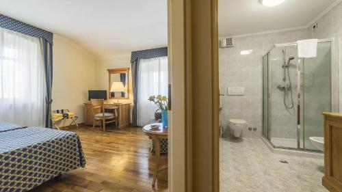 a bedroom with a shower and a bed and a bathroom at Hotel Ville Bianchi in Grado