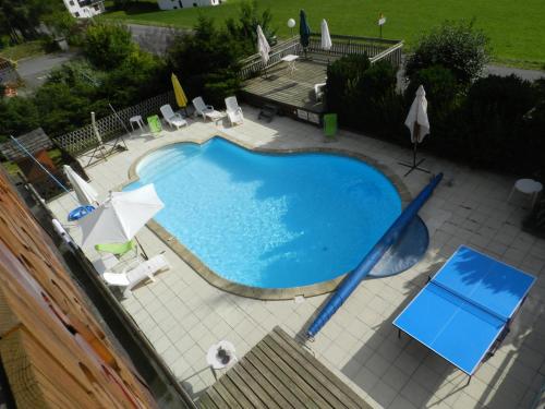 an overhead view of a swimming pool with chairs and umbrellas at Chalet-Hôtel du Borderan in La Clusaz