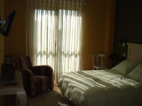 a bedroom with a bed and a chair and a window at Posada la Desmera in Isla
