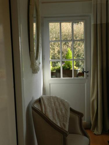 a chair in front of a door with a window at Le Pressoir in Beuvron-en-Auge