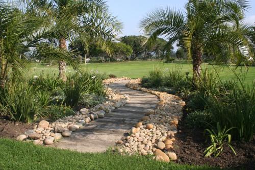 a garden with a stone path and palm trees at Keurbooms River Lodge 21 in Keurboomstrand