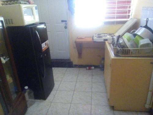 a kitchen with a black refrigerator and a tile floor at Leslies' Home in Portmore