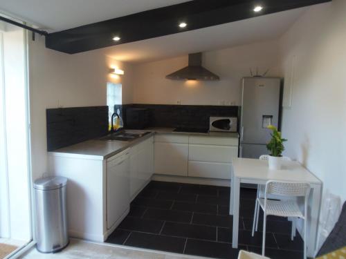 - une cuisine avec des placards blancs, une table et un réfrigérateur dans l'établissement Joli Mazet entre Montpellier et Nimes, à Aimargues