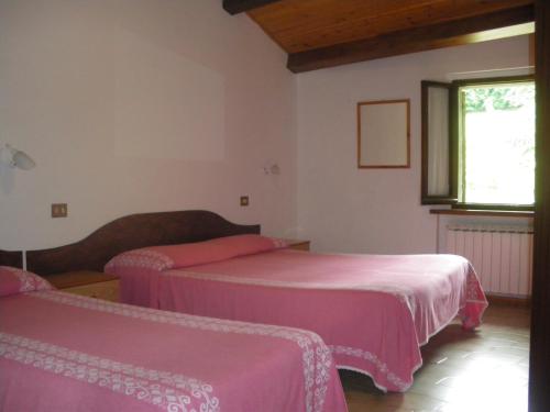 2 Betten in einem Zimmer mit rosa Bettwäsche in der Unterkunft Agriturismo Orsaiola in Urbania