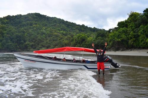 a person standing in the water in front of a boat at Hotel Nuquimar in Nuquí