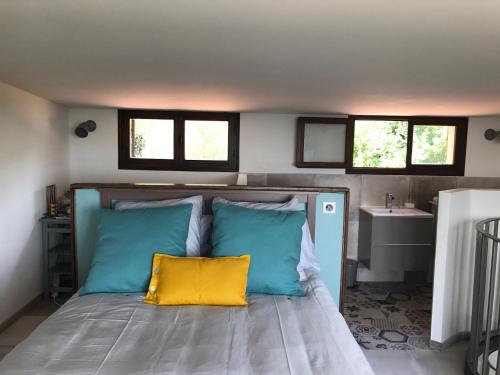 a bedroom with a bed with blue and yellow pillows at Dieu L'Amour - Molinard in Châteauneuf