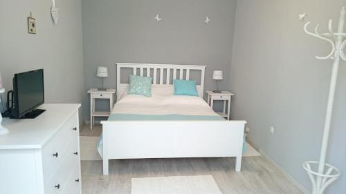 - une chambre blanche avec un lit et des oreillers bleus dans l'établissement Ferencesek apartman, à Pécs