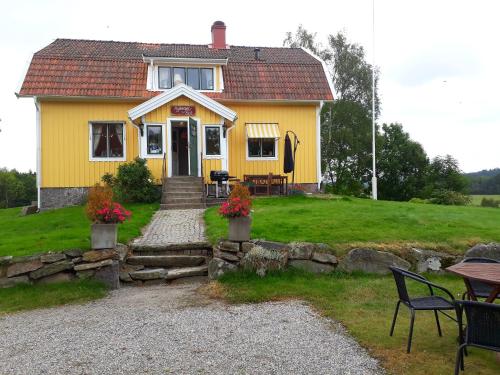 a yellow house with a table and chairs in front of it at Älgbergets Bed & Breakfast in Ucklum