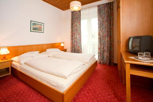 a hotel room with a bed and a tv at Hotel Velden Bacherlwirt in Velden am Wörthersee