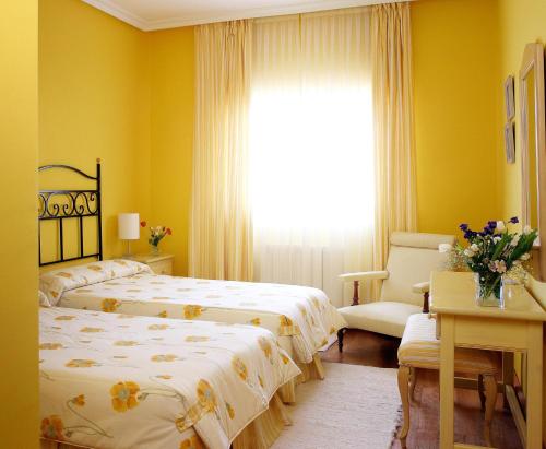 two beds in a room with yellow walls and a window at El Milano Real in Hoyos del Espino