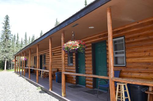 a front porch of a log cabin with flowers on it at Backwoods Lodge in Cantwell